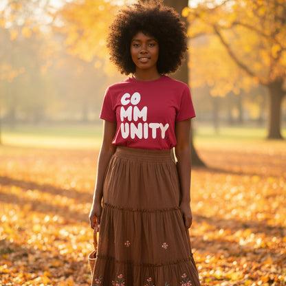 Woman standing in the park on an autumn day wearing the APWT Gift Shop's A Community in Apple Red Unisex T-Shirt from the Community Collection