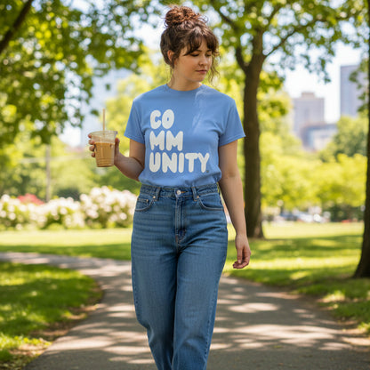 Woman walking through the park wearing the APWT Gift Shop's A Community in Sky Blue Unisex T-Shirt from the Community Collection