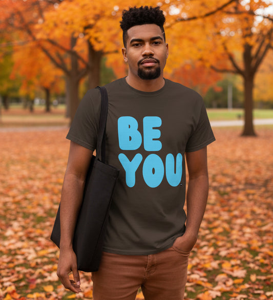 Man standing in the park on an autumn day wearing the APWT Gift Shop's Be You in Brown and Blue Unisex T-Shirt from the Be You Collection
