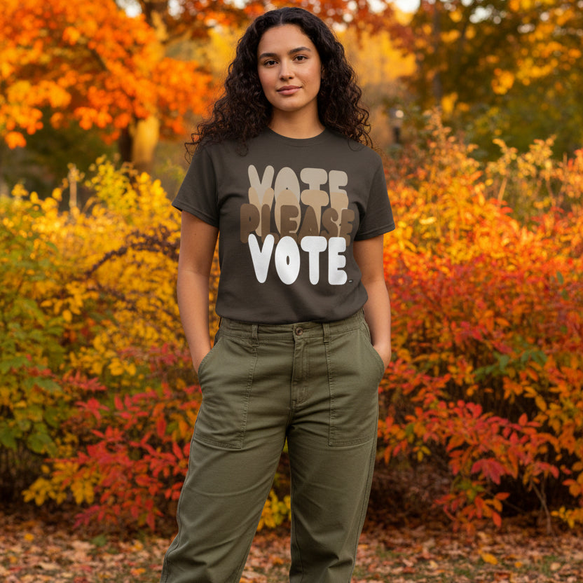 Woman standing in the park on an autumn day wearing the APWT Gift Shop's Please Vote in Brown Love Unisex T-Shirt from the APWT Vote Shop