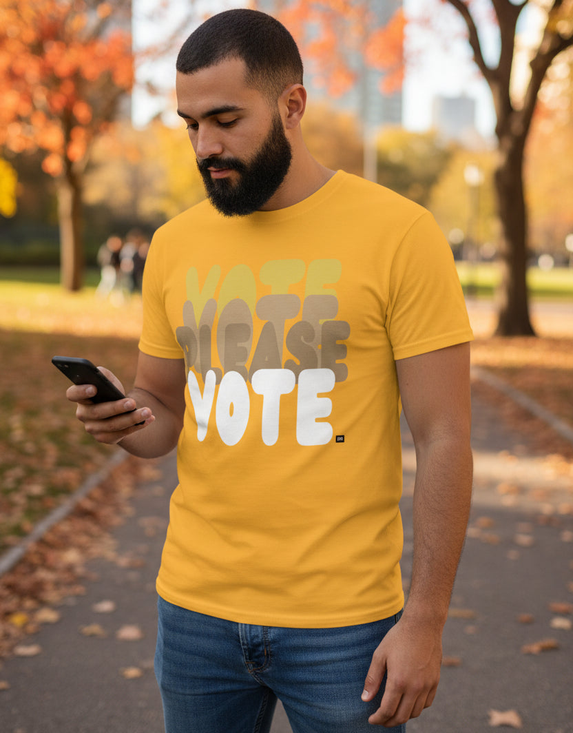 Man standing in the park on an autumn day wearing the APWT Gift Shop's Please Vote in Sunny Yellow Unisex T-Shirt from the APWT Vote Shop