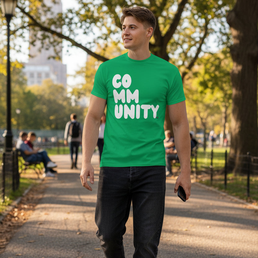 Man walking through the park wearing the APWT Gift Shop's A Community in Green Grass Unisex T-Shirt from the Community Collection