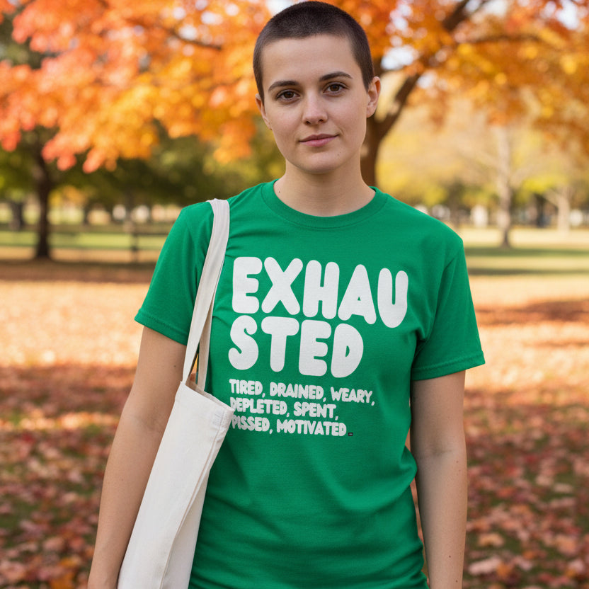 Woman standing in the park on an autumn day wearing the APWT Gift Shop's Exhausted in Green Unisex T-Shirt from the Exhausted Collection