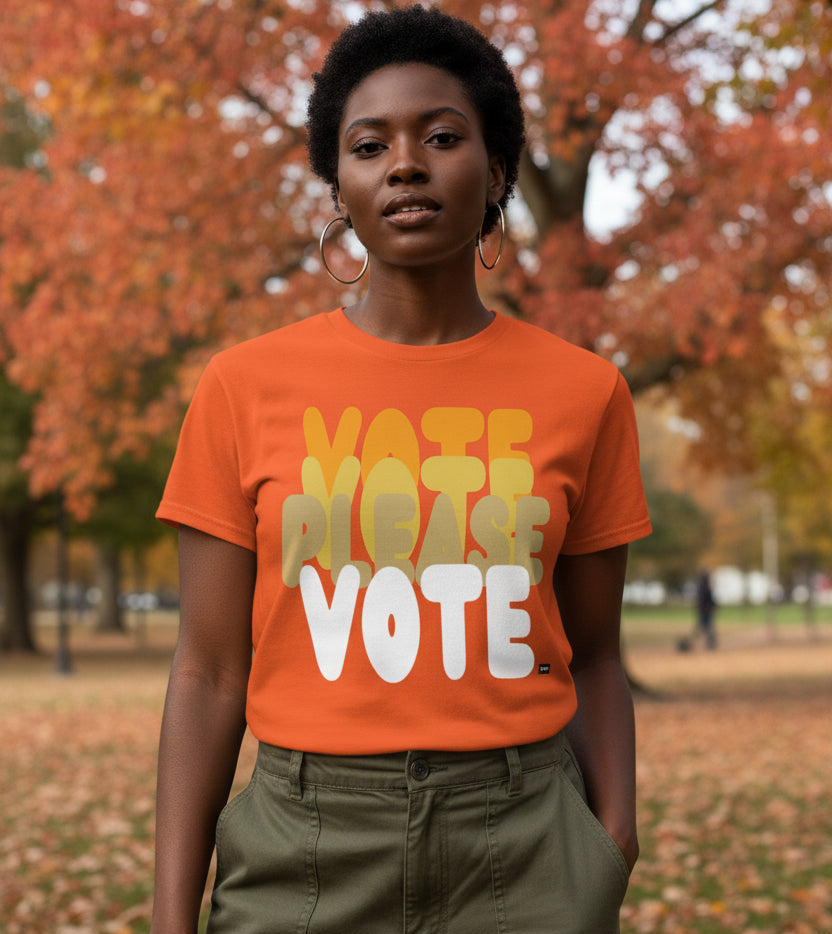 Woman standing in the park on an autumn day wearing the APWT Gift Shop's Please Vote in Safety Cone Orange Unisex T-Shirt from the APWT Vote Shop