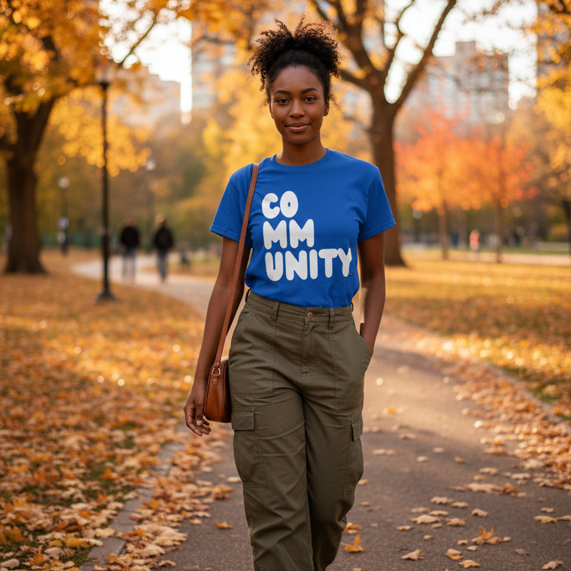 Woman walking through the park on an autumn day wearing the APWT Gift Shop's A Community in Ocean Blue Unisex T-shirt from the Community Collection