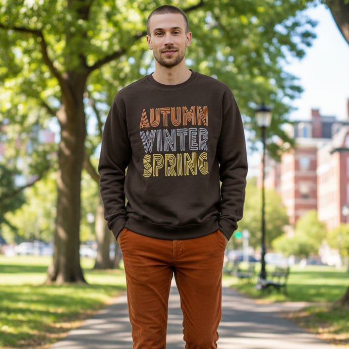 Man walking through the park wearing the APWT Gift Shop's Fall in Autumn Unisex Crew Neck Sweatshirt from the Day in the Life Collection in Brown