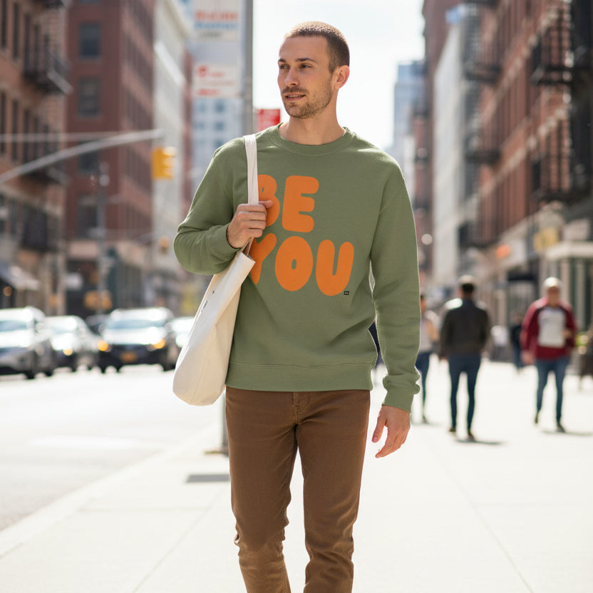 Man walking down the street wearing The APWT Gift Shop's Be You in Olive Green and Orange Unisex Crew Neck Sweatshirt from the Be You Collection 