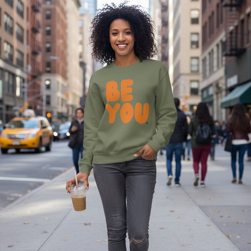 Woman walking down the street wearing The APWT Gift Shop's Be You in Olive Green and Orange Unisex Crew Neck Sweatshirt from the Be You Collection 