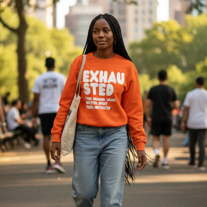 Woman walking through a city park wearing the APWT Gift Shop's Exhausted in Orange Unisex Crew Neck Sweatshirt from the Exhausted Collection