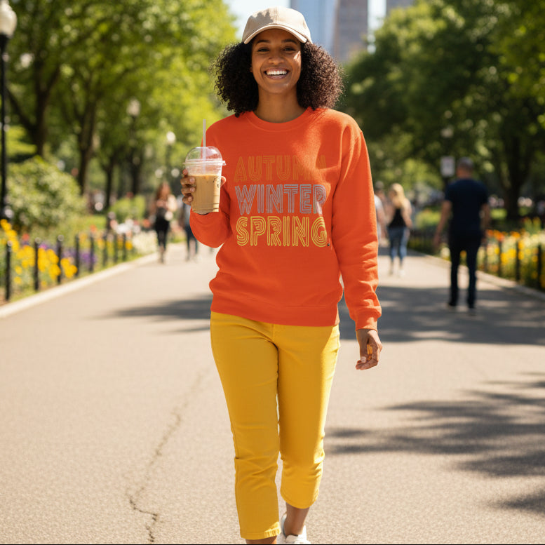 Woman walking through the park wearing the APWT Gift Shop's Fall in Autumn Unisex Crew Neck Sweatshirt from the Day in the Life Collection in Orange