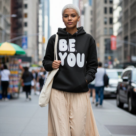 Woman walking down a city street wearing the APWT Gift Shop's Be You in Black and White Premium Unisex Hoodie from the Be You Collection and the Premium Basics Collection
