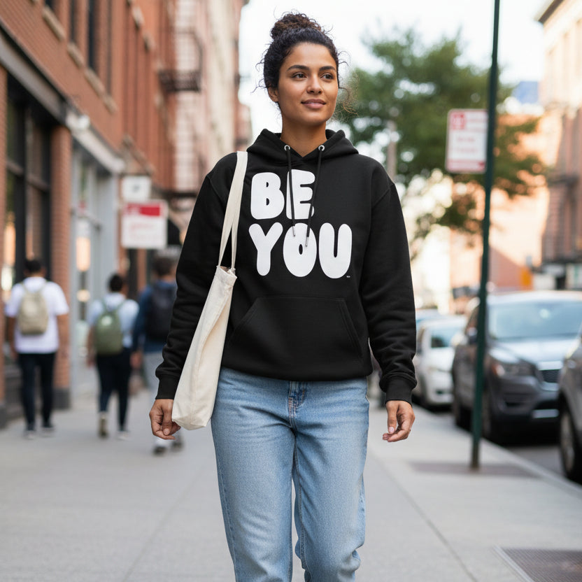 Woman walking down a city street wearing the APWT Gift Shop's Be You in Black and White Premium Unisex Hoodie from the Be You Collection and the Premium Basics Collection