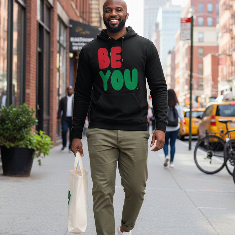 Man walking down the street wearing the APWT Gift Shop's Be You in Black Premium Unisex Hoodie from the Black Collection and Premium Basics Collection