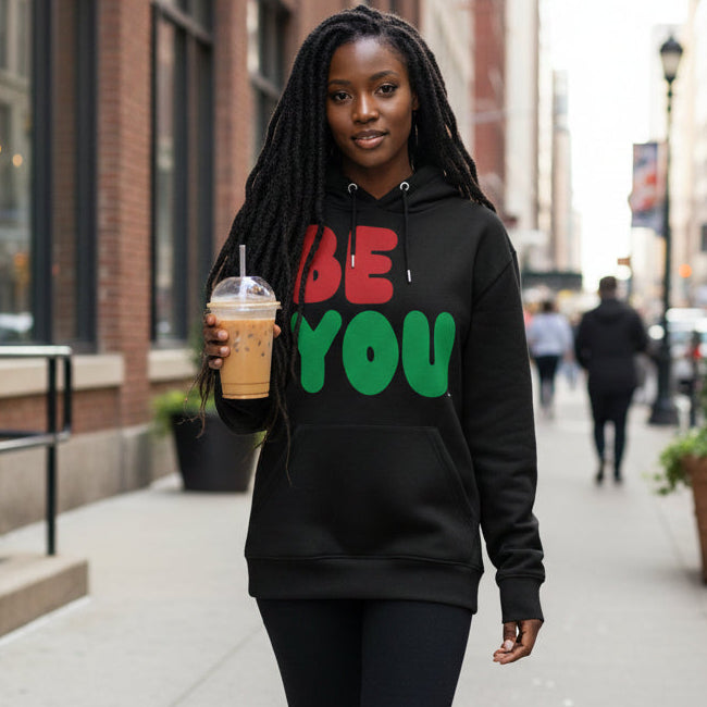 Woman walking down the street wearing the APWT Gift Shop's Be You in Black Premium Unisex Hoodie from the Black Collection and Premium Basics Collection