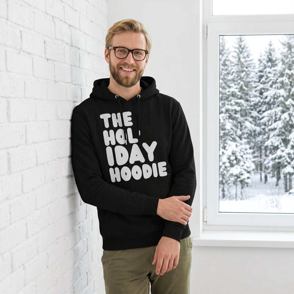 Man standing in a white room wearing The APWT Gift Shop's The Holiday Celebration Premium Unisex Hoodie from the APWT Holiday Shop and the Day in the Life Collection