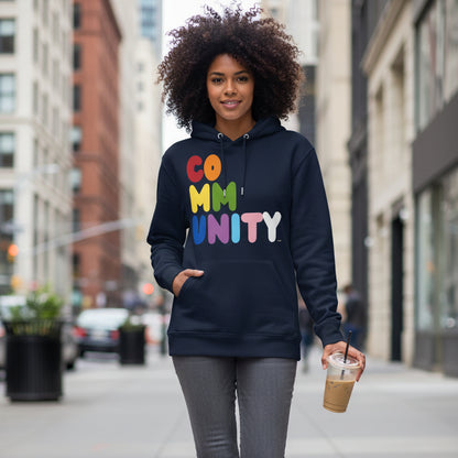 Woman walking down a city sidewalk wearing the APWT Gift Shop's Rainbow Community Premium Unisex Hoodie from the Community Collection and the Pride in the APWT Gift Shop Collection