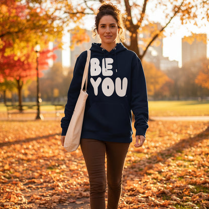 Woman walking through a city park on an autumn day wearing the APWT Gift Shop's Be You in Blue and White Premium Unisex Hoodie from the Be You Collection