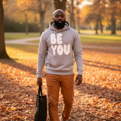 man walking through a city park on an autumn day wearing the APWT Gift Shop's Be You in Grey and White Premium Unisex Hoodie from the Be You Collection