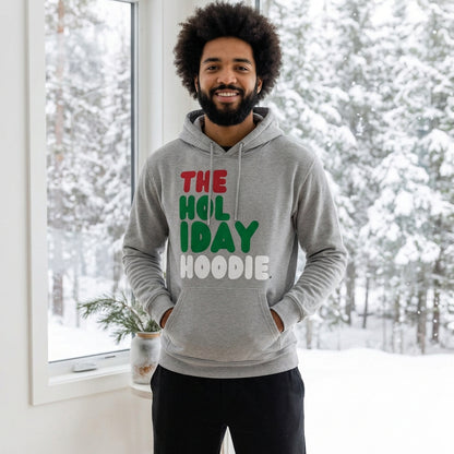 Man standing in a white room wearing The Holiday Hoodie Premium Unisex Hoodie from the APWT Holiday Shop and the Day in the Life Collection in Grey