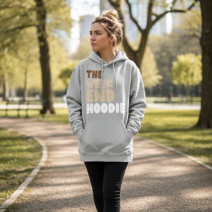 Woman walking through a city park wearing the APWT Gift Shop's The Weekend Hoodie Premium Unisex Hoodie from the Day in the Life Collection and the Premium Basics Collection in a grey