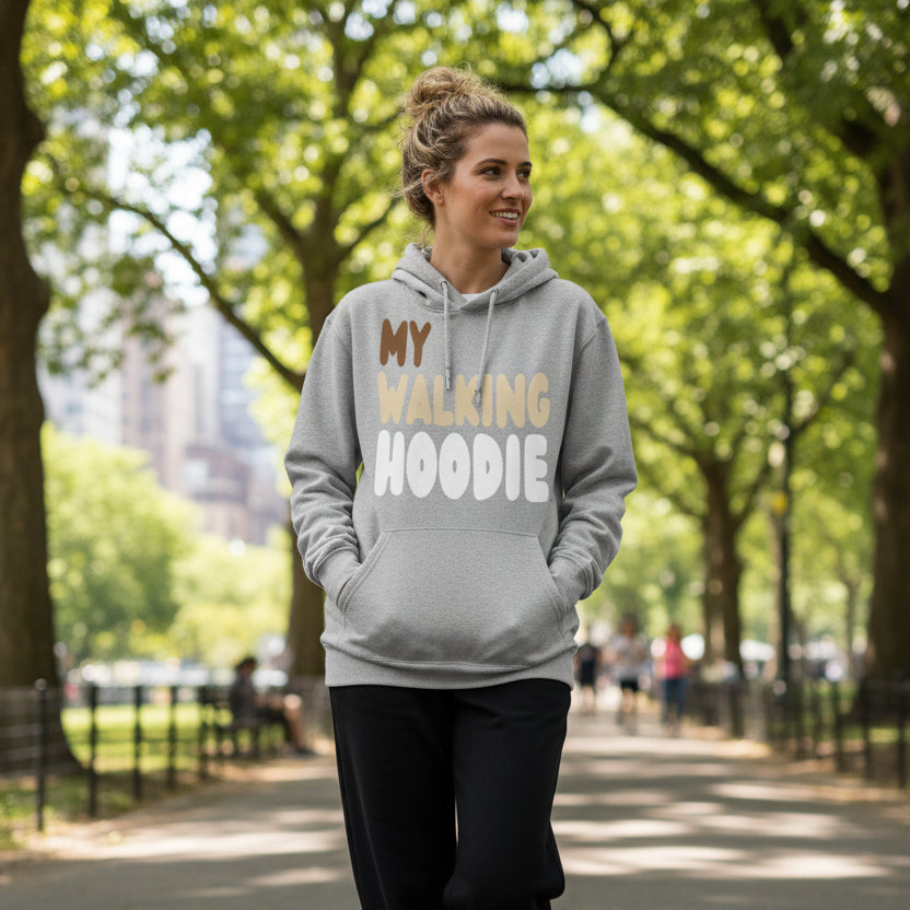 Woman walking through a city park wearing the APWT Gift Shop's My Walking Hoodie Premium Unisex Hoodie from the Day in the Life Collection in Grey