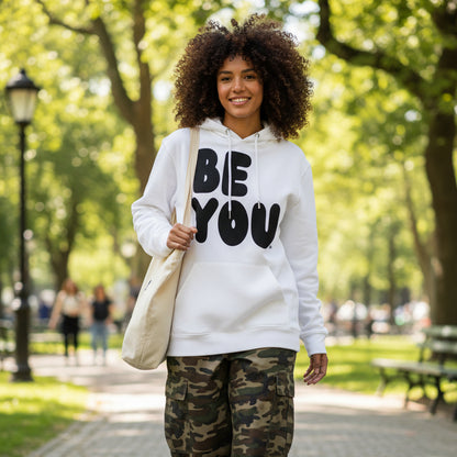 Woman walking through a city park  wearing the APWT Gift Shop's Be You in Black and White Premium Unisex White Hoodie from the Be You Collection