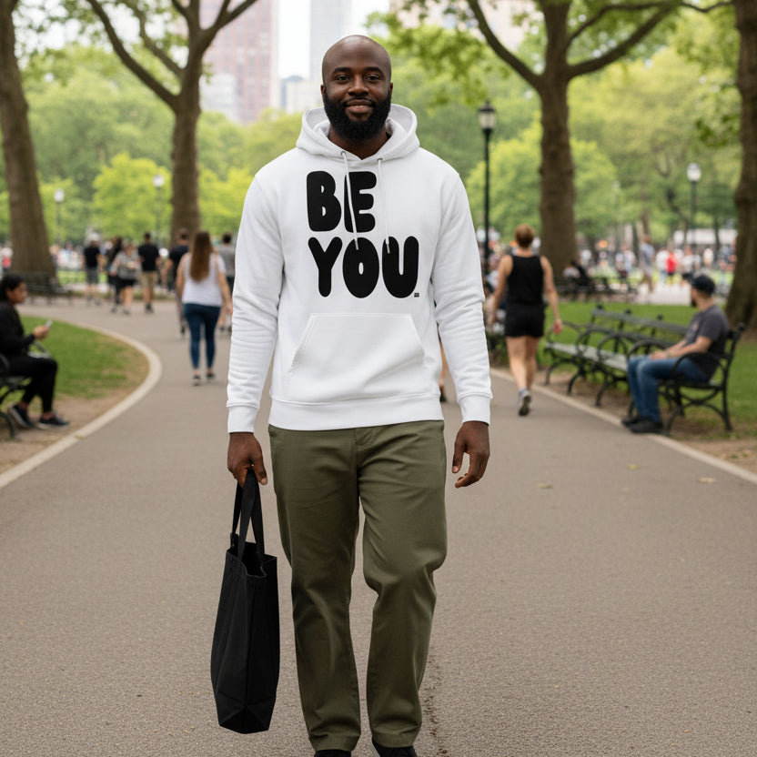 man walking through a city park  wearing the APWT Gift Shop's Be You in Black and White Premium Unisex White Hoodie from the Be You Collection