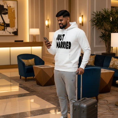 Man in hotel lobby wearing the APWT Gift Shop's Just Married Premium Unisex Hoodie from the APWT Wedding Shop