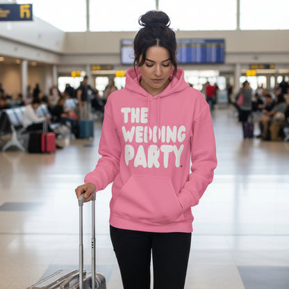 Woman standing in the airport wearing the APWT Gift Shop's The Wedding Party Unisex Hoodie from the APWT Wedding Shop in Pink