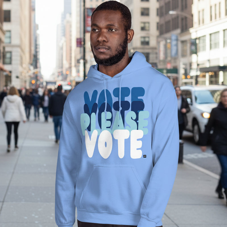 Man on a city street wearing Please Vote in Sky Blue Unisex Hoodie from the APWT Gift Shop -  Vote Advocacy Sweatshirt
