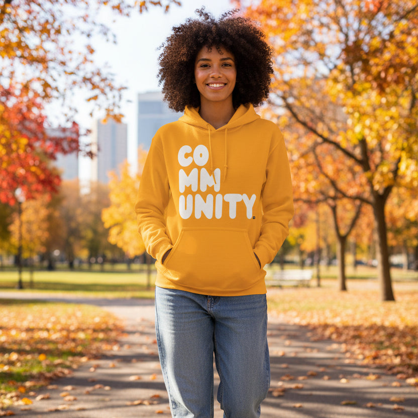 Woman walking through a city park wearing the APWT Gift Shop's A Community in Sunny Yellow Unisex Hoodie from the Community Collection