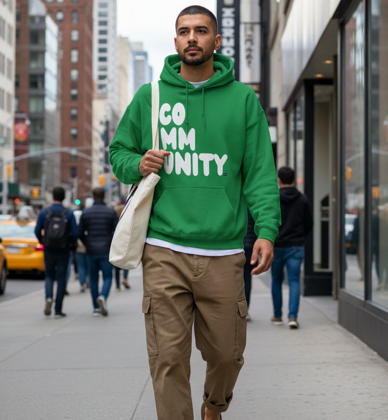 Man walking down the street wearing the APWT Gift Shop's A Community in Green Grass Unisex Hoodie from the Community Collection