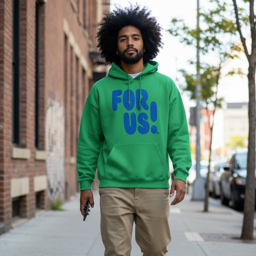 Man walking down a city sidewalk wearing the APWT Gift Shop's For Us in Green and Blue Unisex Hoodie from the For Us Collection