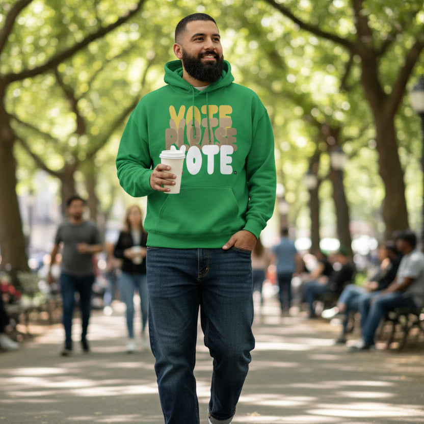 Man walking through a city park wearing the APWT Gift Shop's Please Vote in Green Spaces Unisex Hoodie from the APWT Vote Shop