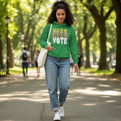 Woman walking through a city park wearing the APWT Gift Shop's Please Vote in Green Spaces Unisex Hoodie from the APWT Vote Shop