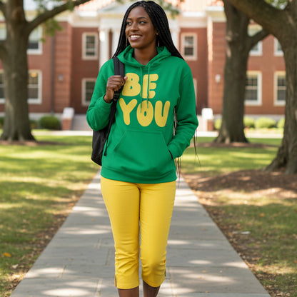 Woman walking on a college campus wearing the APWT Gift Shop's Be You in Green and Yellow Unisex Hoodie from the Be You Collection