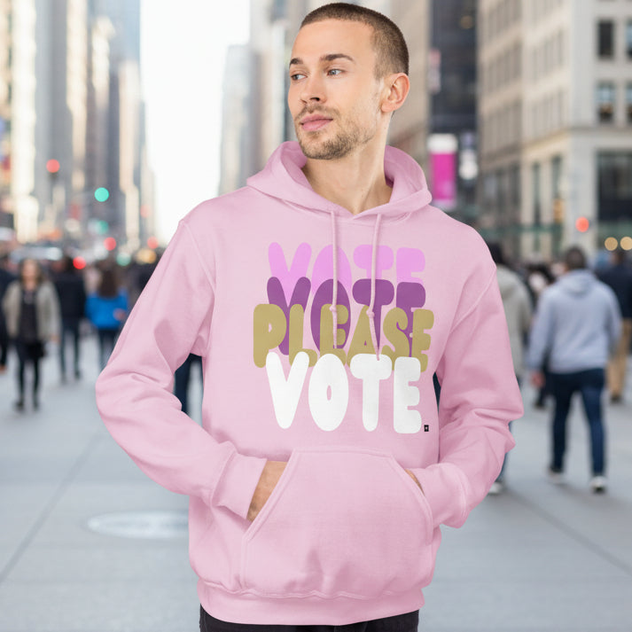 Man on a city street wearing Please Vote in Primaries Pink Unisex Hoodie from the APWT Gift Shop -  Vote Advocacy Sweatshirt