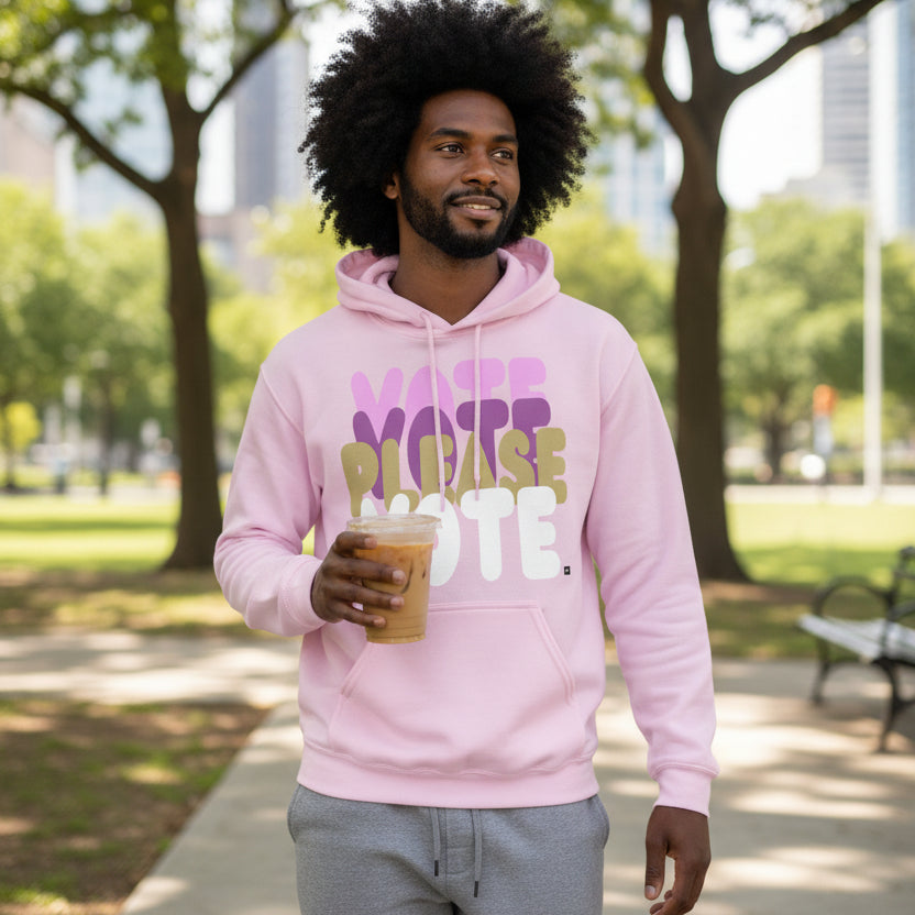 Man walking through a city park wearing the APWT Gift Shop's Please Vote in Primaries Pink Unisex Hoodie from the APWT Vote Shop