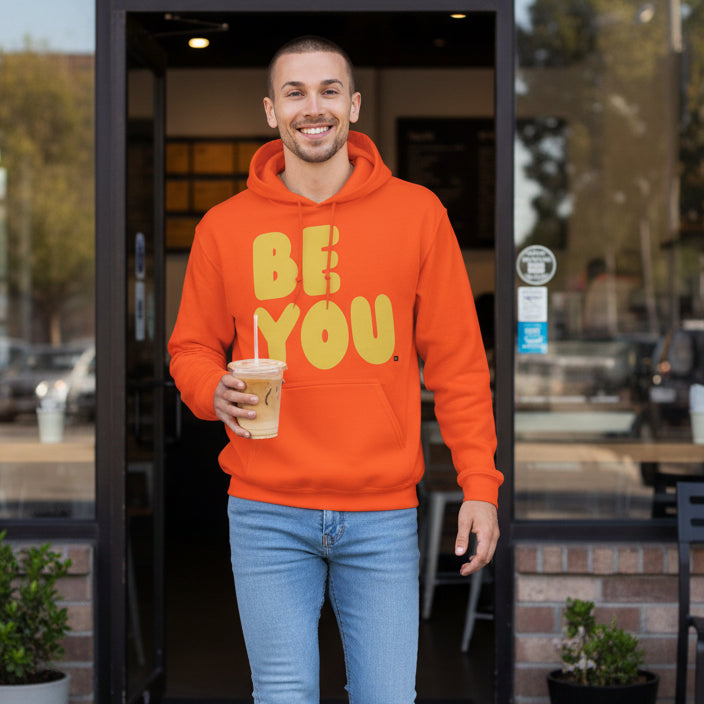 man walking out of a cafe wearing the APWT Gift Shop's Be You in Orange and Yellow Unisex Hoodie from the Be You Collection