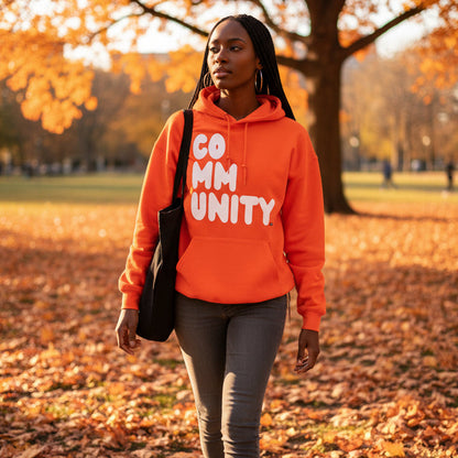 Woman walking through the park wearing the APWT Gift Shop's A Community in Orange Citrus Unisex Hoodie from the Community Collection