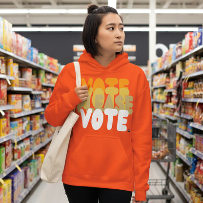 Woman walking through a grocery store wearing the APWT Gift Shop's Please Vote in Safety Cone Orange Unisex Hoodie from the APWT Vote Shop