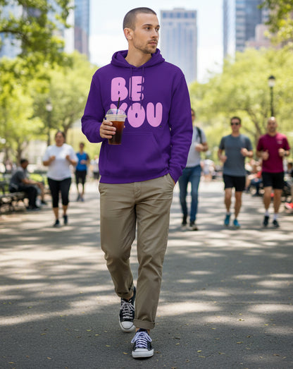 man walking through a city park wearing the APWT Gift Shop's Be You in Purple and Pink Unisex Hoodie from the Be You Collection