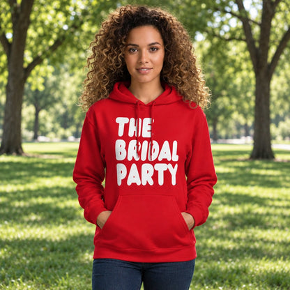 Woman standing in a park wearing the APWT Gift Shop's The Bridal Party Unisex Hoodie from the APWT Wedding Shop in Red