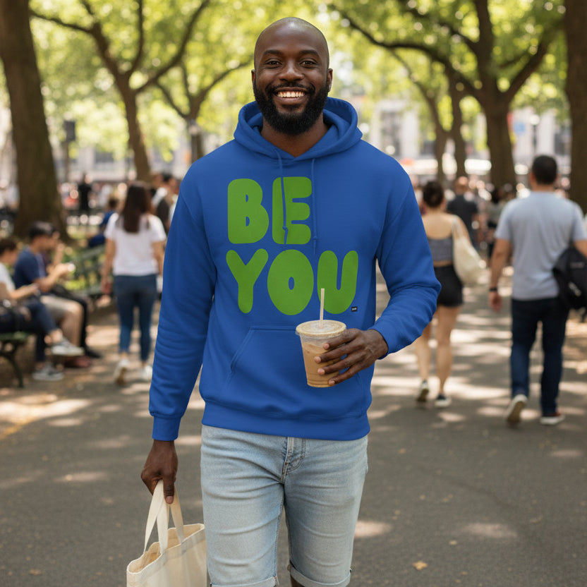 man walking through a city park wearing the APWT Gift Shops Be You in Blue and Green Unisex Hoodie from the Be You Collection