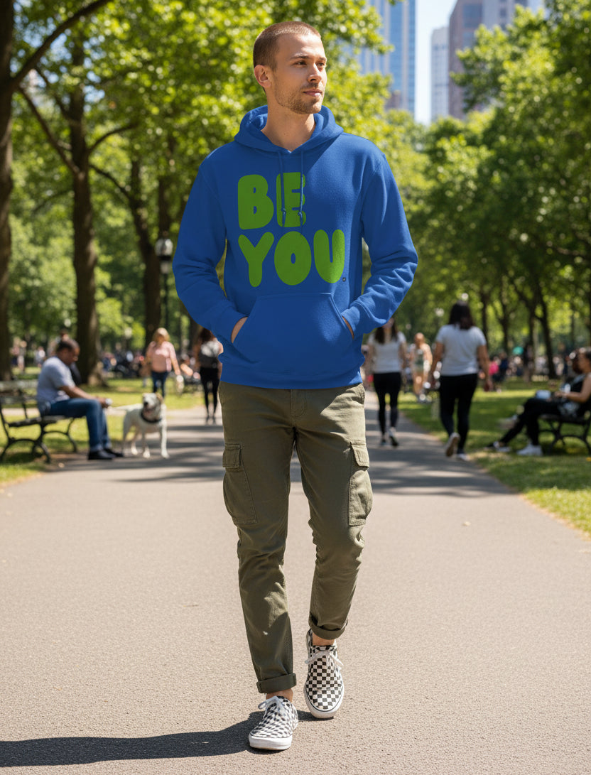 man walking through a city park wearing the APWT Gift Shops Be You in Blue and Green Unisex Hoodie from the Be You Collection