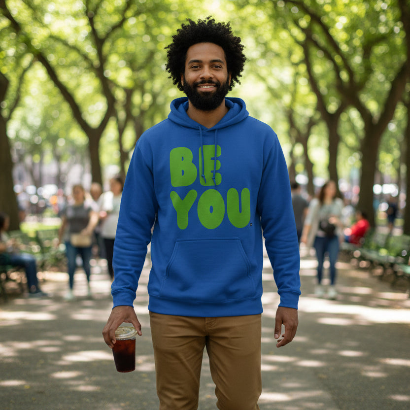 man walking through a city park wearing the APWT Gift Shops Be You in Blue and Green Unisex Hoodie from the Be You Collection