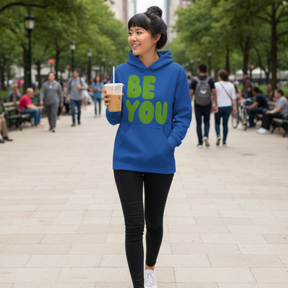 Woman walking through a city park wearing the APWT Gift Shops Be You in Blue and Green Unisex Hoodie from the Be You Collection