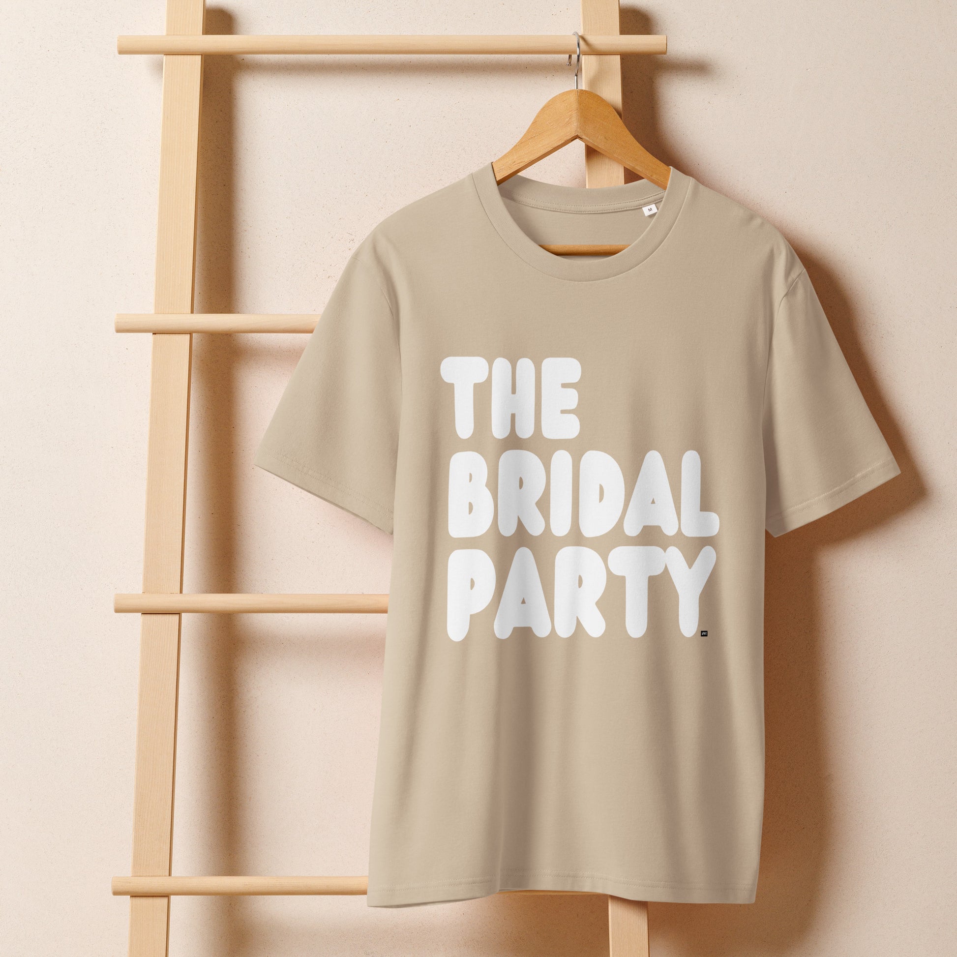The Bridal Party Premium Unisex T-Shirt in Beige on a hanger