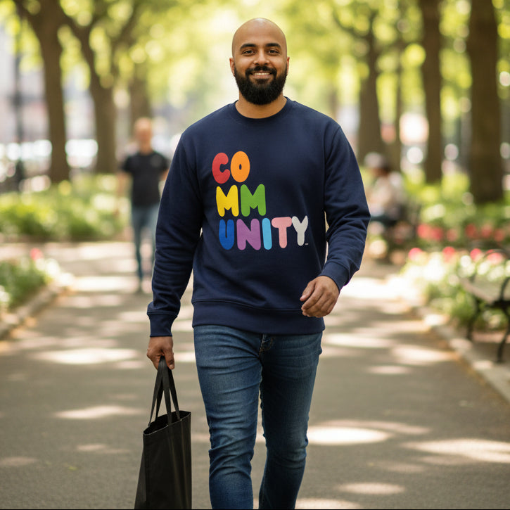 man walking through city park wearing the APWT Gift Shop's Rainbow Community Premium Unisex Crew Neck Sweatshirt from the Community Collection and the Premium Basics Collection 