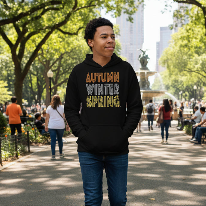 Boy walking through a city park wearing The APWT Gift Shop's Fall into Autumn Kid's Unisex Hoodie in Black from the APWT Kid's Shop